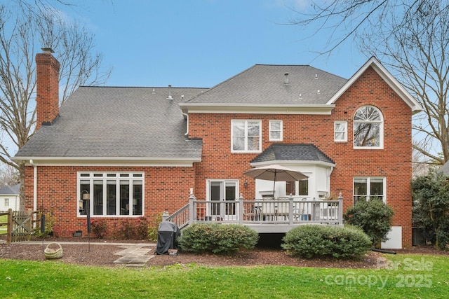 rear view of house featuring a wooden deck and a yard