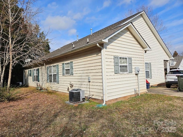 view of side of home featuring central AC and a yard