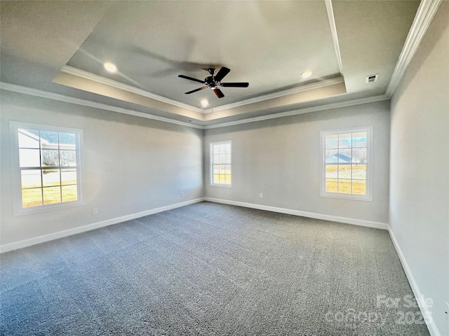 empty room with carpet floors, visible vents, baseboards, ornamental molding, and a raised ceiling