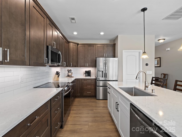 kitchen with a sink, visible vents, dark wood-style flooring, and stainless steel appliances