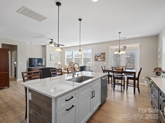 kitchen with visible vents, light wood finished floors, a sink, hanging light fixtures, and dishwasher