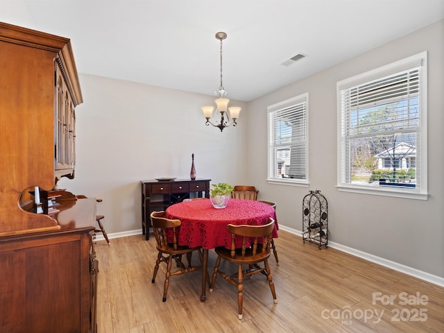 dining room featuring a notable chandelier, visible vents, light wood-type flooring, and baseboards