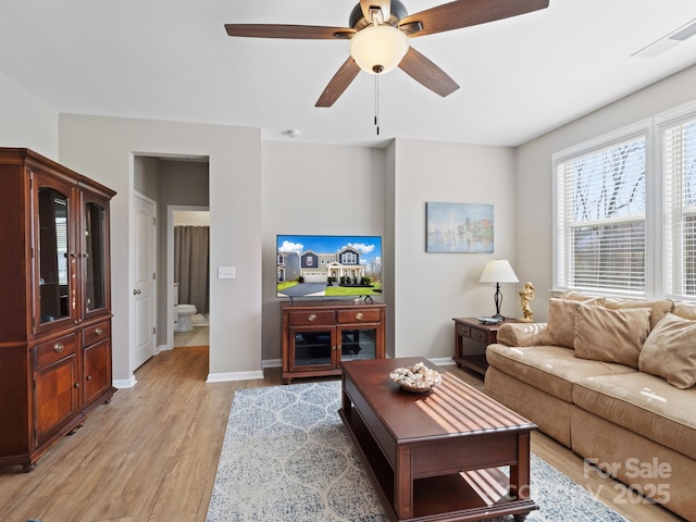 living area with light wood finished floors, visible vents, a ceiling fan, and baseboards