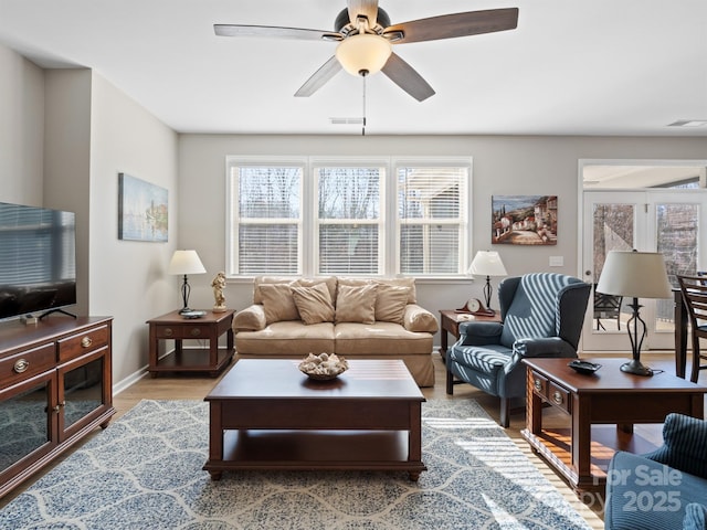 living area with visible vents, baseboards, ceiling fan, and light wood finished floors