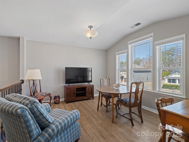 dining room featuring vaulted ceiling, baseboards, visible vents, and light wood finished floors