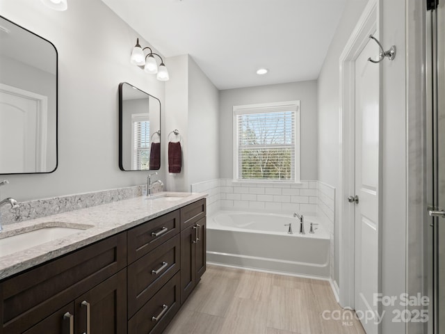 full bath featuring double vanity, a garden tub, and a sink