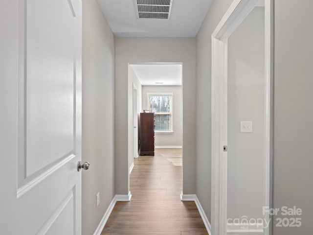 hall with visible vents, dark wood-type flooring, and baseboards