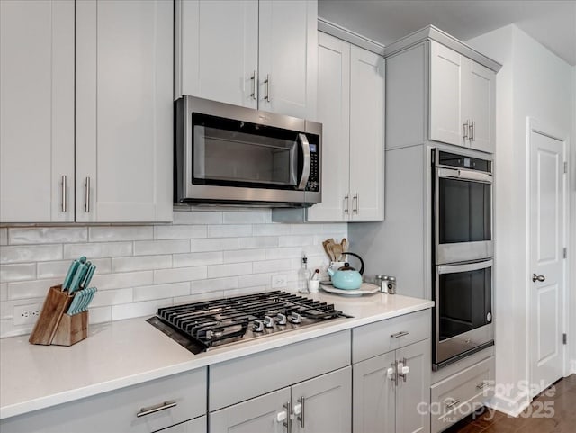 kitchen featuring stainless steel appliances, white cabinets, and backsplash