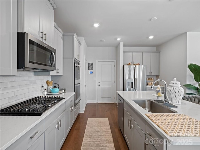 kitchen featuring sink, tasteful backsplash, a center island with sink, dark hardwood / wood-style floors, and stainless steel appliances