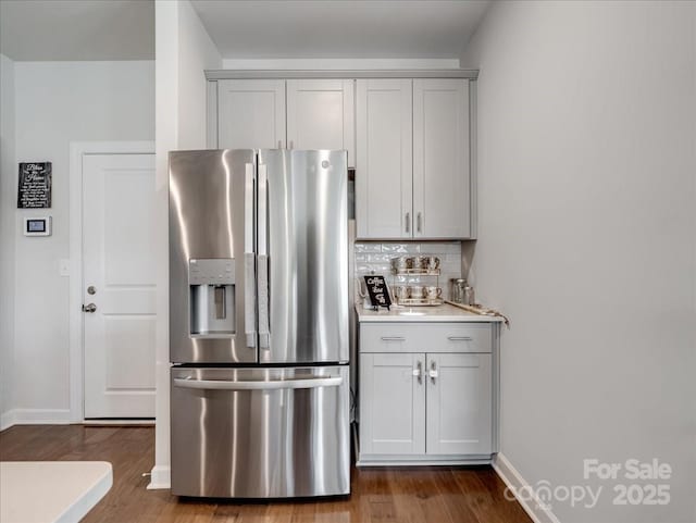 kitchen featuring hardwood / wood-style floors, stainless steel fridge, and decorative backsplash