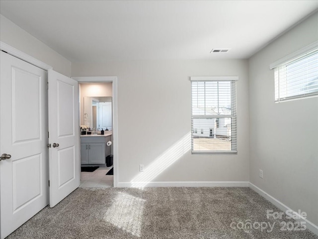 unfurnished bedroom with light colored carpet and connected bathroom