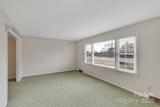 carpeted empty room with a textured ceiling