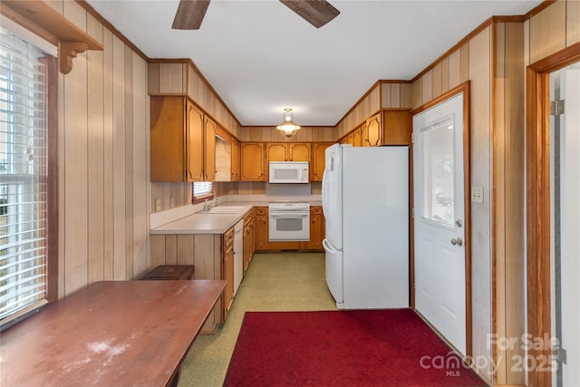 kitchen featuring ornamental molding, sink, white appliances, and wood walls