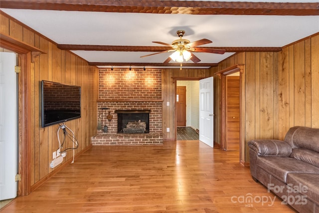 living room with a fireplace, wooden walls, and light hardwood / wood-style floors