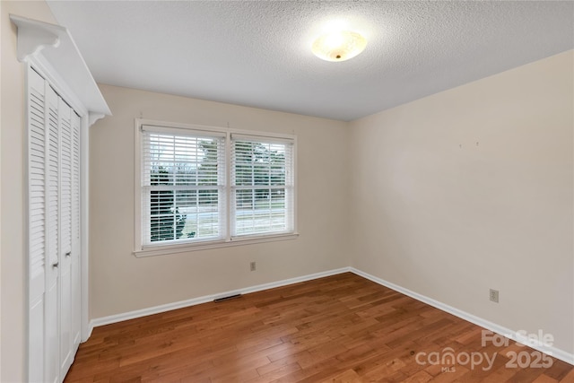 unfurnished bedroom featuring hardwood / wood-style flooring, a textured ceiling, and a closet