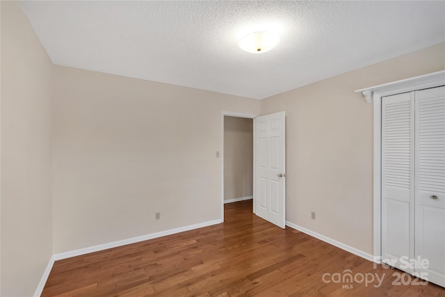 unfurnished bedroom featuring hardwood / wood-style floors, a closet, and a textured ceiling