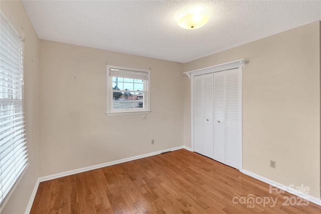 unfurnished bedroom with hardwood / wood-style floors, a closet, and a textured ceiling