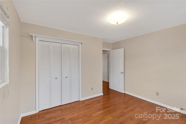 unfurnished bedroom with hardwood / wood-style floors, a closet, and a textured ceiling