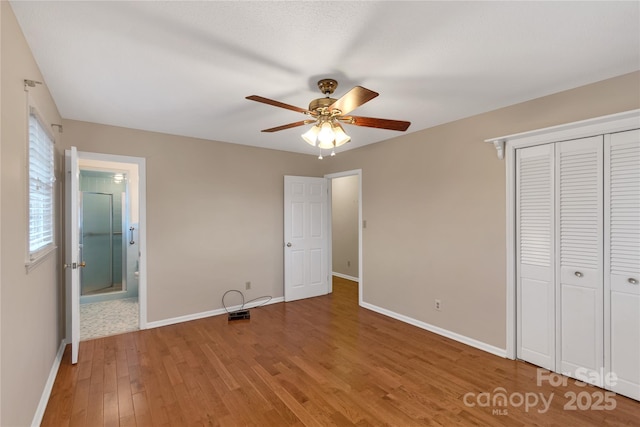 unfurnished bedroom featuring wood-type flooring, ceiling fan, ensuite bath, and a closet