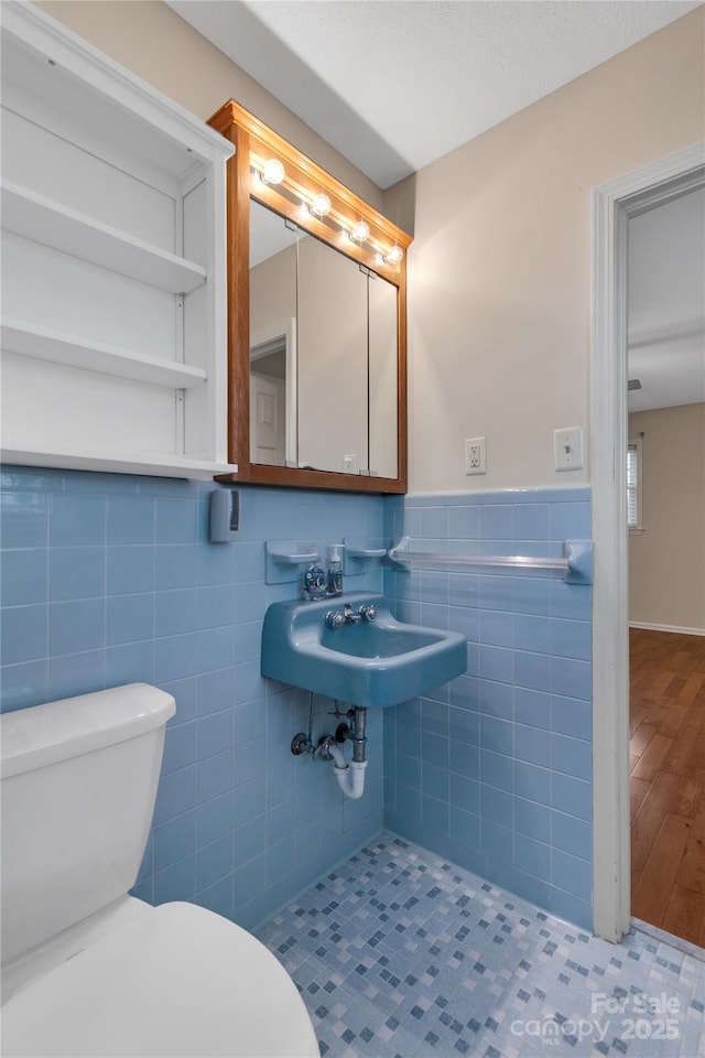 bathroom with sink, tile walls, and toilet