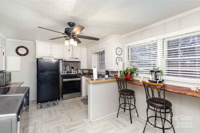 kitchen with a breakfast bar, appliances with stainless steel finishes, white cabinetry, butcher block counters, and kitchen peninsula