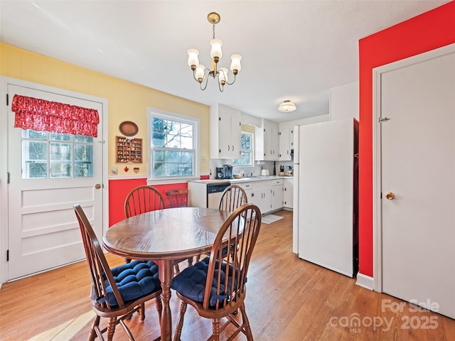 dining room with sink, a chandelier, and light wood-type flooring