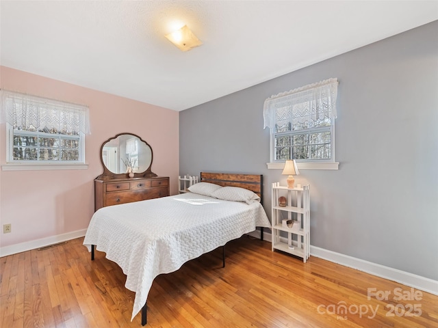 bedroom with multiple windows and hardwood / wood-style floors