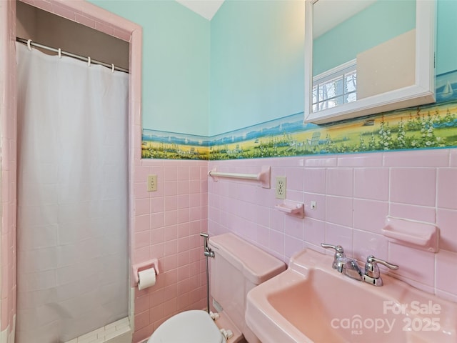 bathroom featuring a shower with curtain, toilet, sink, and tile walls