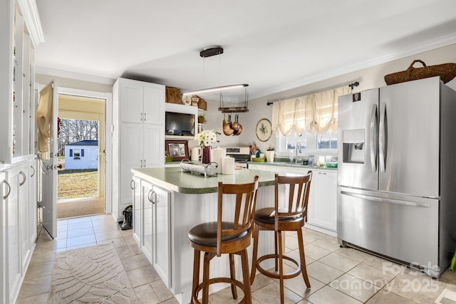 kitchen featuring crown molding, white cabinetry, a kitchen island, stainless steel appliances, and a kitchen bar