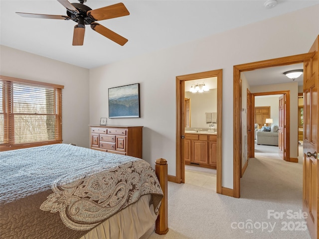 bedroom with ensuite bath, light colored carpet, and ceiling fan