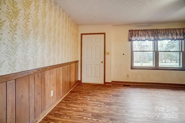 unfurnished room featuring wood-type flooring and a textured ceiling