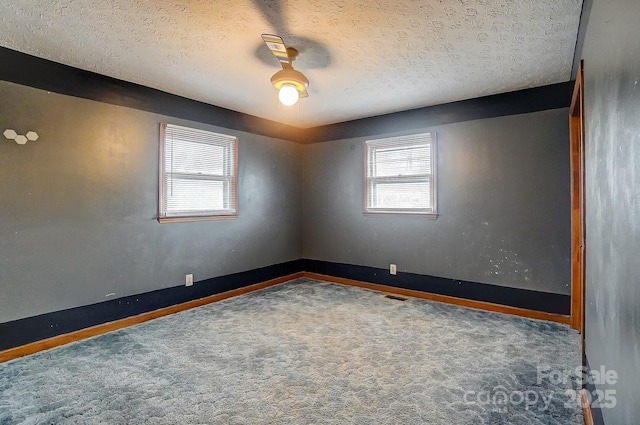 carpeted empty room featuring a textured ceiling