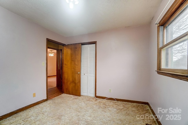 unfurnished bedroom featuring carpet flooring, a textured ceiling, and a closet