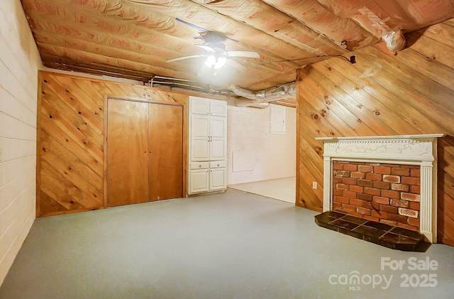 bonus room featuring concrete floors, ceiling fan, and wood walls