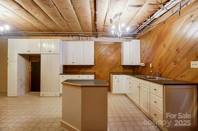 kitchen with white cabinetry, sink, and wood walls