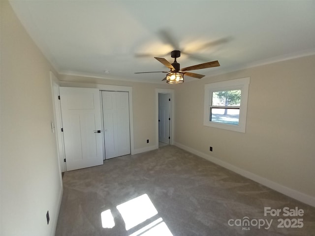 unfurnished bedroom with ornamental molding, carpet flooring, ceiling fan, and a closet