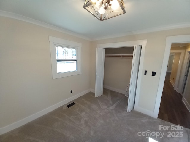 unfurnished bedroom with crown molding, dark carpet, and a closet