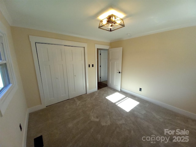 unfurnished bedroom with ornamental molding, a closet, and carpet flooring