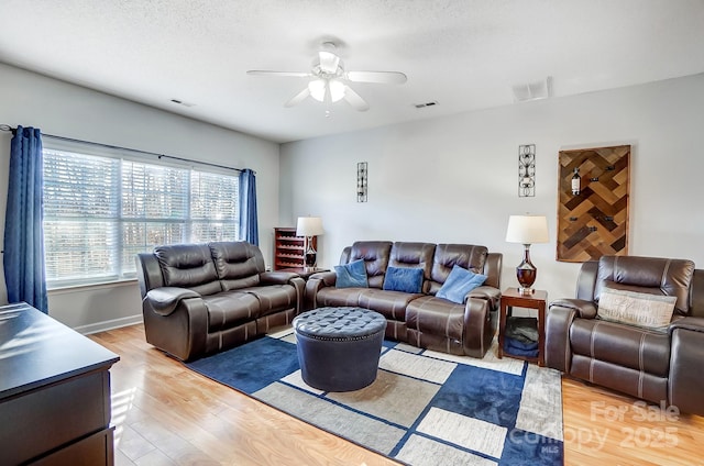 living room featuring ceiling fan, hardwood / wood-style flooring, and a textured ceiling