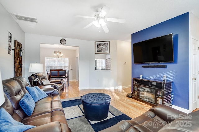 living room featuring hardwood / wood-style flooring and ceiling fan with notable chandelier