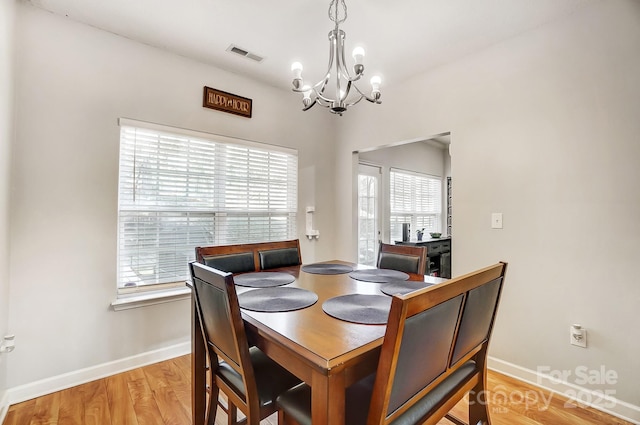 dining space featuring plenty of natural light, light hardwood / wood-style floors, and a chandelier