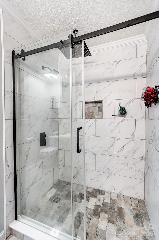 bathroom featuring ornamental molding, a shower with shower door, and a textured ceiling