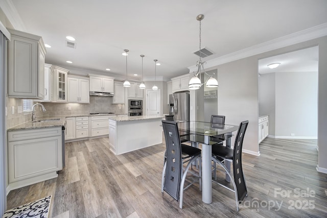 dining area with sink, crown molding, and light hardwood / wood-style floors