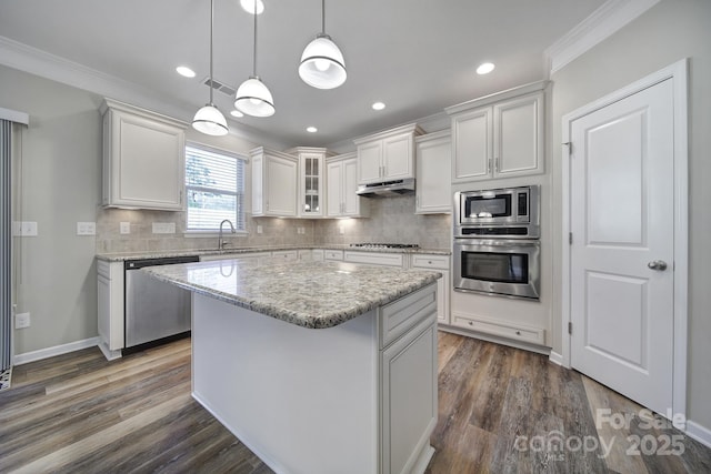 kitchen featuring appliances with stainless steel finishes, decorative light fixtures, a center island, dark hardwood / wood-style flooring, and white cabinetry