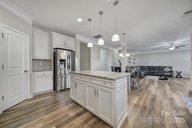 kitchen featuring white cabinetry, a center island, stainless steel refrigerator with ice dispenser, ornamental molding, and pendant lighting