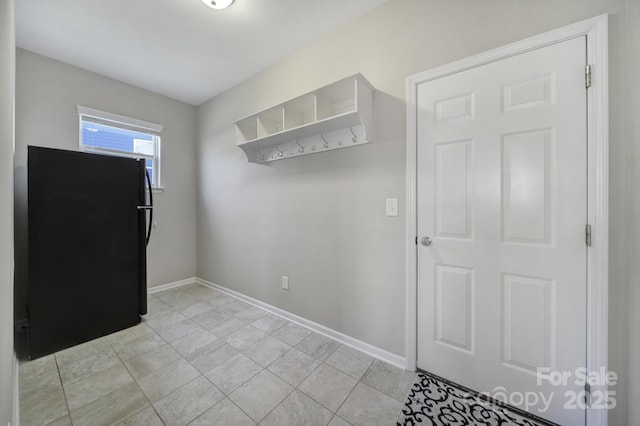 interior space with light tile patterned floors and black fridge