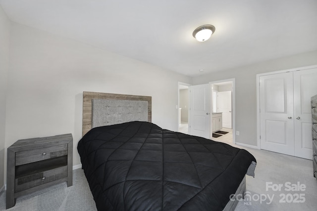 bedroom featuring a closet, ensuite bath, and light colored carpet