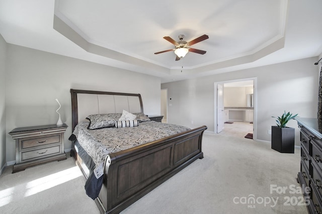 bedroom with ceiling fan, a raised ceiling, light carpet, and connected bathroom