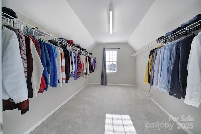 walk in closet with vaulted ceiling and light colored carpet