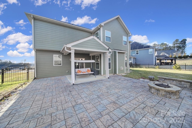 rear view of property with a yard, a patio area, a gazebo, and a fire pit